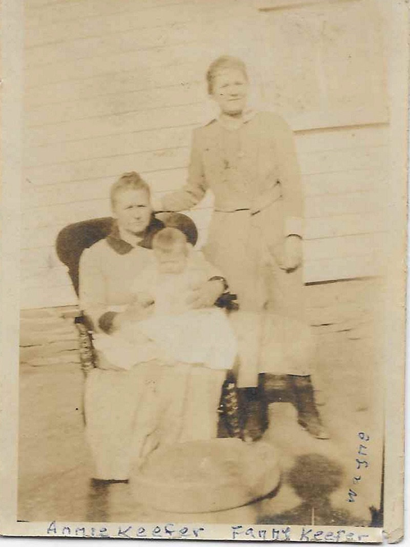 An old photo of a woman holding a baby in a chair, while another woman stands behind her, labeled "Annie Keefer, Fanny Keefer"